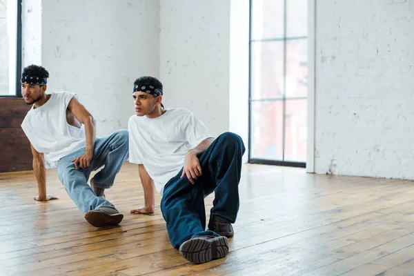 Homens multiculturais bonitos em headbands posando enquanto dança hip-hop — Fotografia de Stock