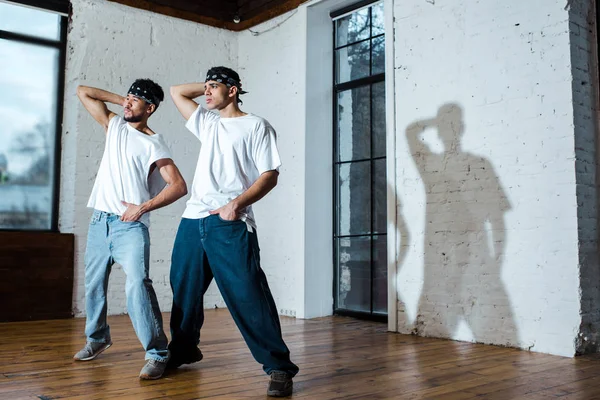 Внимание на красивых мультикультурных танцоров в повязках на голове, позирующих в танцевальной студии — стоковое фото