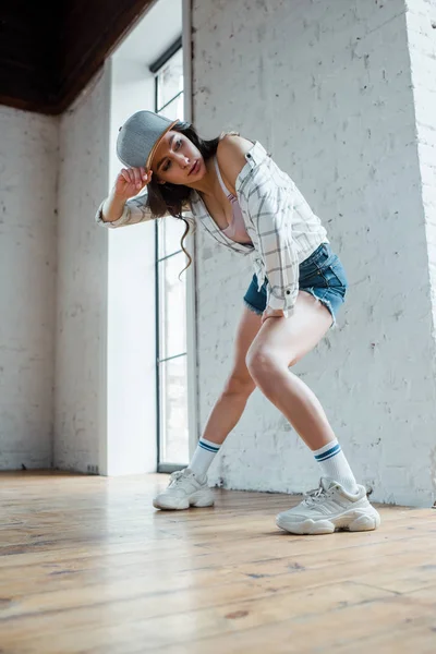 Attractive dancer touching cap while dancing hip-hop — Stock Photo