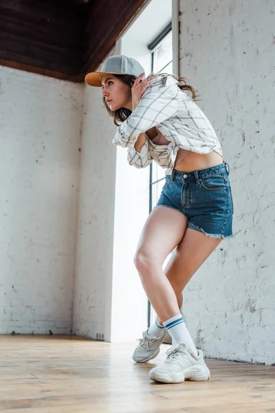 Привлекательная танцовщица в шляпе, позирующая во время танца хип-хопа — стоковое фото