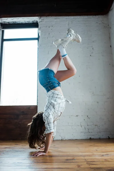 Jeune danseuse faisant handstand en studio de danse — Photo de stock