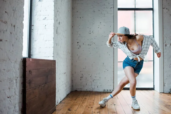 Молодая женщина трогает кепку и танцует хип-хоп — стоковое фото
