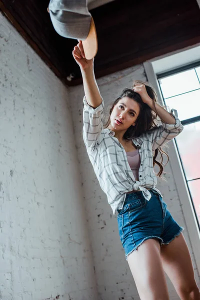 Messa a fuoco selettiva di graziosa ballerina che tiene il cappuccio e tocca i capelli in studio di danza — Foto stock