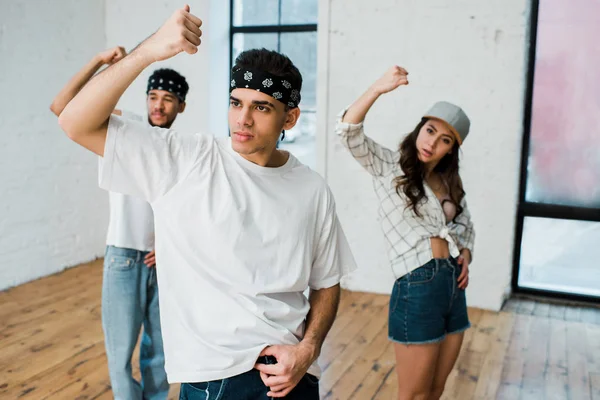 Focus selettivo dell'uomo e dei ballerini multiculturali che ballano hip-hop in studio di danza — Foto stock