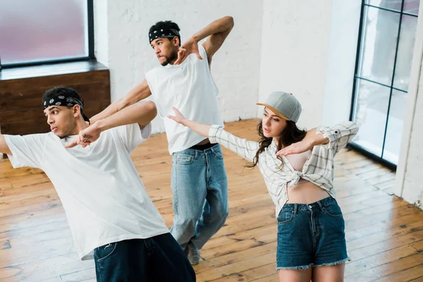 Bailarines multiculturales haciendo gestos mientras bailan hip-hop en el estudio de danza - foto de stock