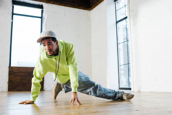 Handsome african american man in cap breakdancing in dance studio — Stock Photo