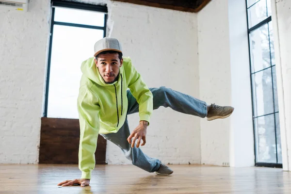 Young african american man in cap breakdancing in dance studio — Stock Photo