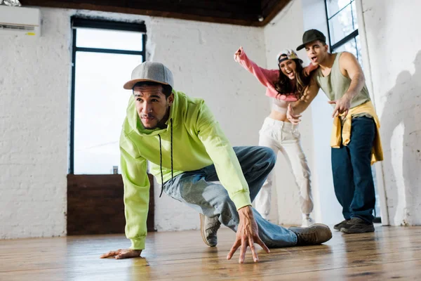 Selective focus of handsome african american dancer breakdancing near emotional man and woman — Stock Photo