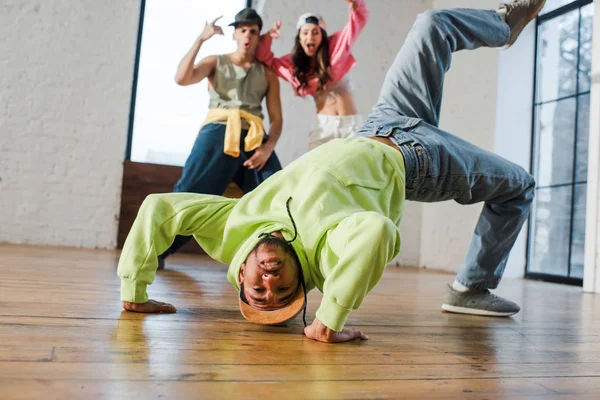 Enfoque selectivo del hombre afroamericano breakdance cerca de bailarines emocionales - foto de stock