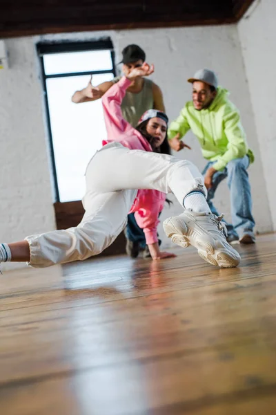 Selektiver Fokus von Mädchen-Breakdance in der Nähe emotionaler multikultureller Männer — Stockfoto