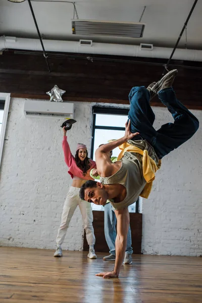Selective focus of man breakdancing near excited multicultural dancers — Stock Photo