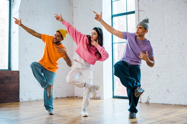 Stylish woman and multicultural men gesturing and breakdancing — Stock Photo
