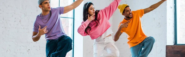 Panoramic shot of young woman and stylish multicultural men breakdancing — Stock Photo