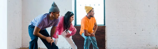Panoramic shot of woman and stylish multicultural men breakdancing — Stock Photo