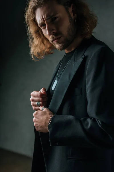 Tenso homem de negócios na moda em terno preto posando no escuro — Fotografia de Stock