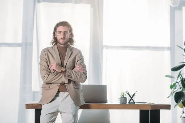 Elegante uomo d'affari alla moda in piedi vicino alla scrivania in ufficio — Foto stock