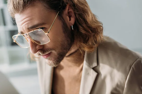 Hombre de negocios de moda en pendientes y anteojos mirando a la cámara - foto de stock