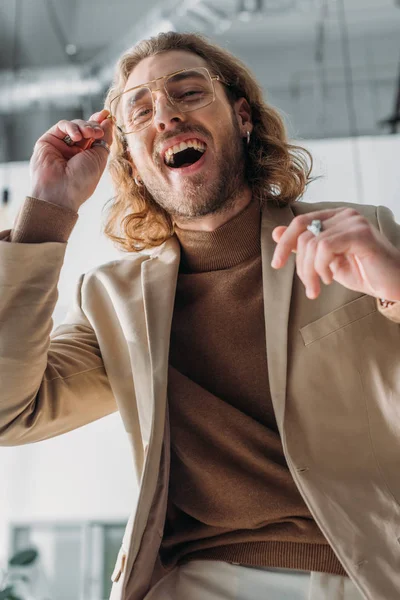 Vista de ángulo bajo de hombre de negocios de moda en gafas riendo de la cámara - foto de stock