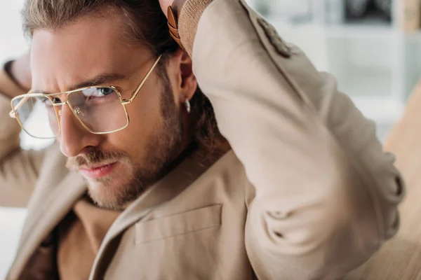 Close up view of fashionable businessman in eyeglasses posing with hands behind head — Stock Photo