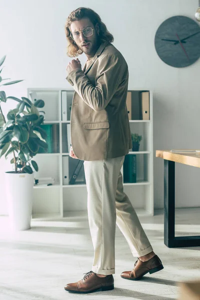 Vista lateral de elegante hombre de negocios de moda posando en la luz del sol en la oficina - foto de stock