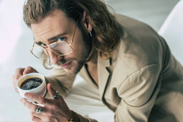 Vista aérea de elegante homem de negócios elegante segurando xícara de café no escritório — Fotografia de Stock