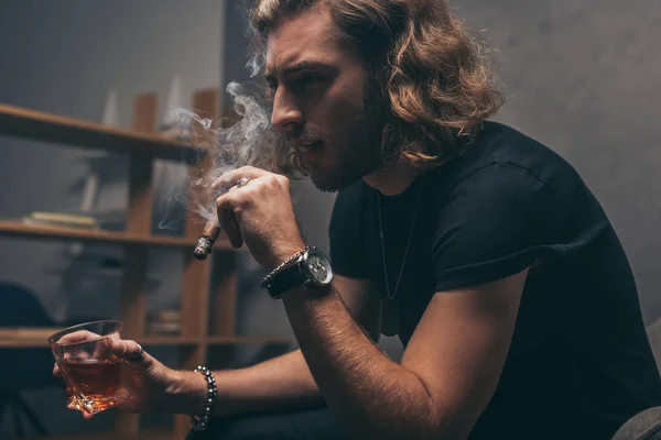 Модний бізнесмен в чорному вбранні курить сигару і п'є віскі — стокове фото