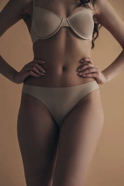 Vista cortada de menina sexy em lingerie com as mãos em quadris isolados em bege — Fotografia de Stock