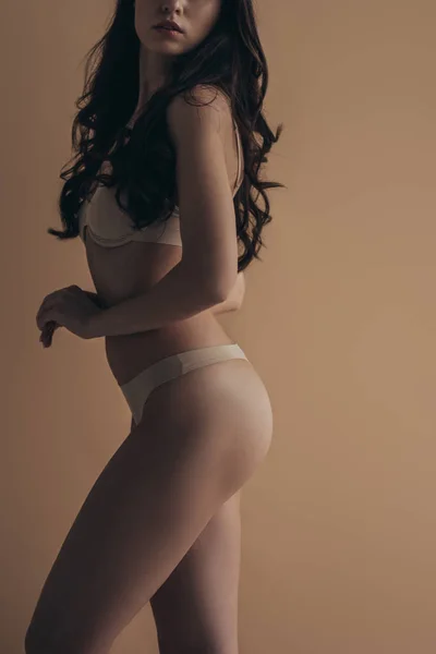 Vista lateral de la hermosa mujer sexy en ropa interior aislada en beige - foto de stock