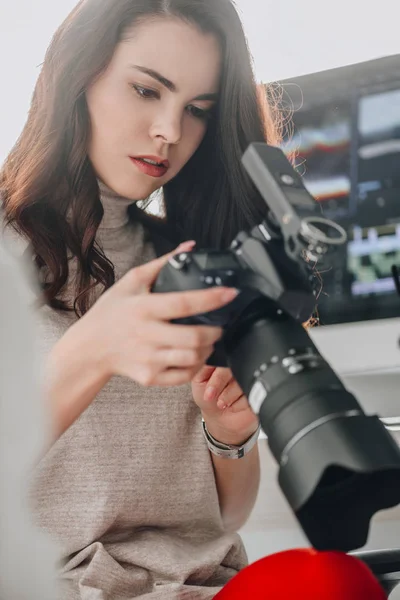 Foco seletivo do editor de arte atraente segurando câmera digital perto do monitor do computador — Fotografia de Stock