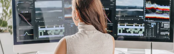 Panoramic shot of filmmaker working near computer monitors — Stock Photo