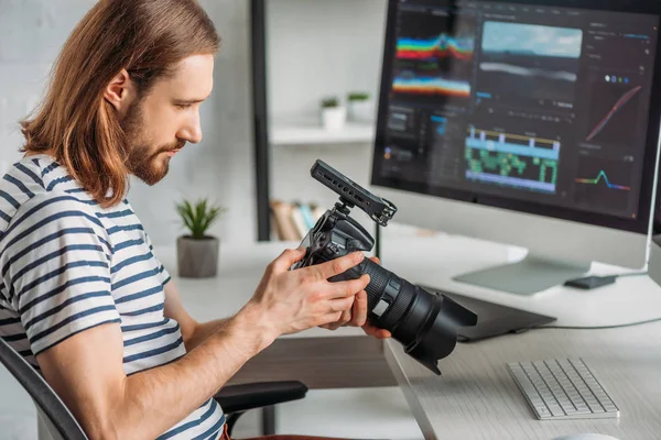 Vue latérale de l'éditeur tenant un appareil photo numérique — Photo de stock