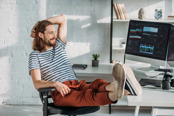 Heureux cinéaste reposant près des moniteurs d'ordinateur en studio — Photo de stock