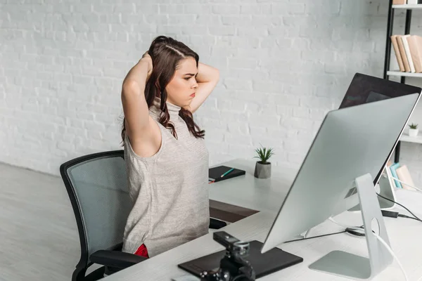 Tired art editor looking at computer monitors — Stock Photo