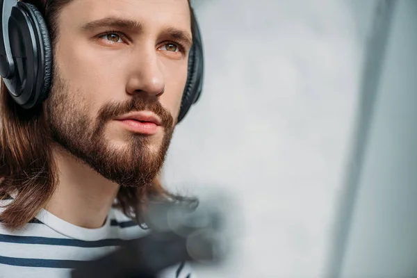 Handsome bearded editor listening music in headphones — Stock Photo