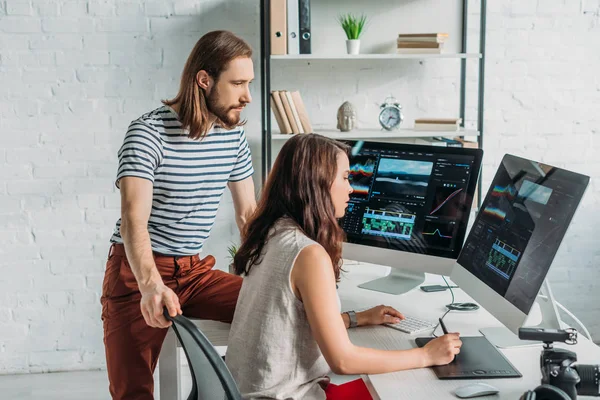 Bärtiger Kunstredakteur in der Nähe attraktiver Mitarbeiter, die im Atelier arbeiten — Stockfoto