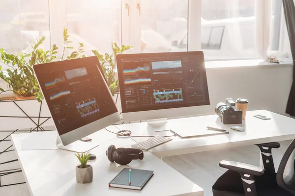 Computer monitors with storyboard near digital camera on table — Stock Photo