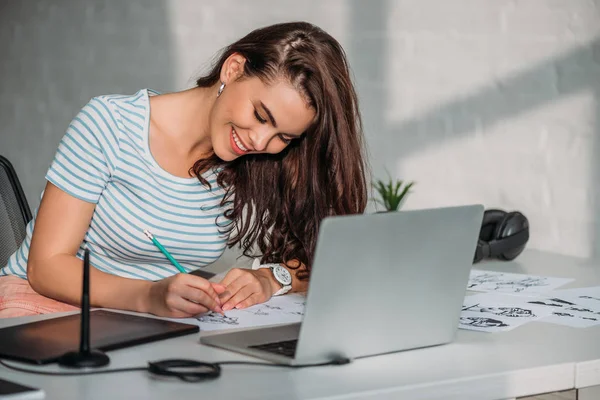 Happy illustrator drawing cartoon character on paper — Stock Photo