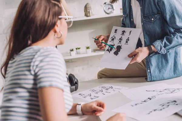 Vista cortada do ilustrador segurando desenhos animados esboços perto da mulher — Fotografia de Stock