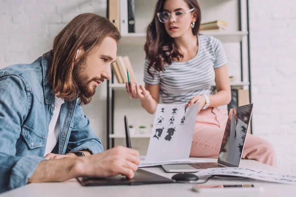 Selective focus of bearded animator working near attractive coworker — Stock Photo