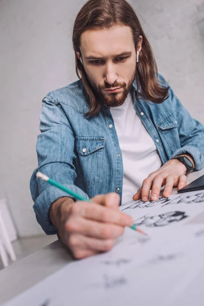 Selective focus of bearded illustrator drawing cartoon sketches on paper — Stock Photo