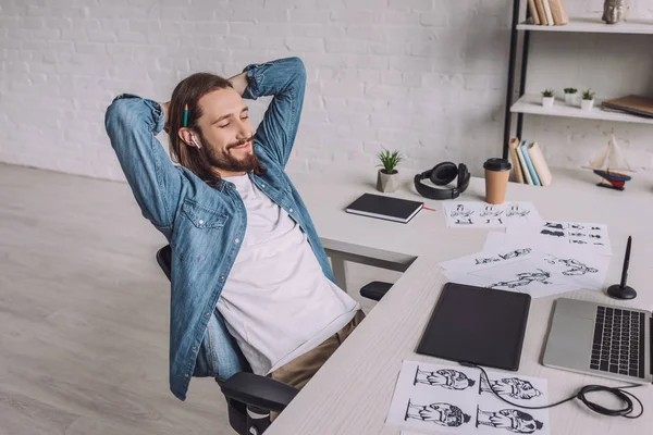 Ilustrador alegre sonriendo cerca de gadgets y bocetos - foto de stock