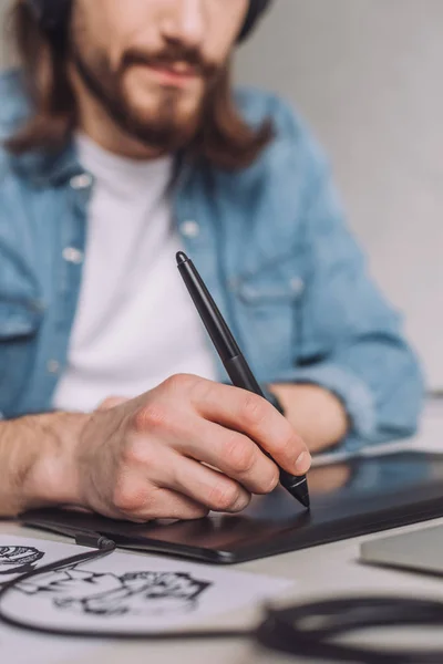 Selective focus of animator using digital tablet near paper with sketches — Stock Photo