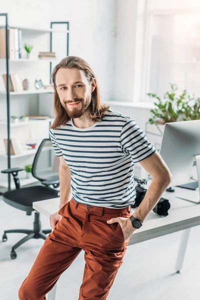 Cheerful art editor smiling while posing with hands in pockets — Stock Photo