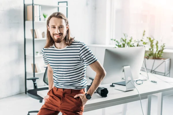 Joyeux éditeur d'art barbu souriant tout en posant avec les mains dans les poches — Photo de stock