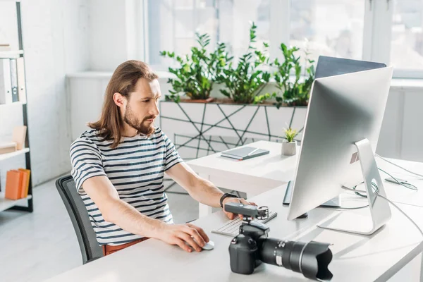 Bärtige Redakteurin arbeitet in der Nähe von Digitalkameras im Studio — Stockfoto