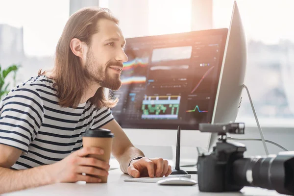 Selektiver Fokus des bärtigen Redakteurs, der Pappbecher in der Hand hält und auf den Computermonitor blickt — Stockfoto