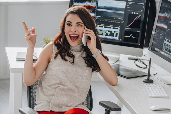 Excited art editor talking on smartphone near computer monitors — Stock Photo