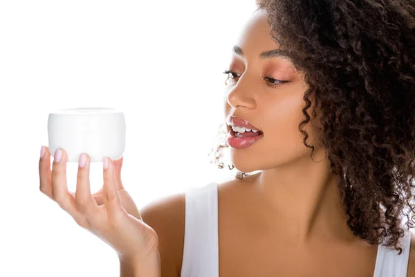 Junge lächelnde afrikanisch-amerikanische Frau hält Plastikbehälter mit Gesichtscreme, isoliert auf weiß — Stockfoto