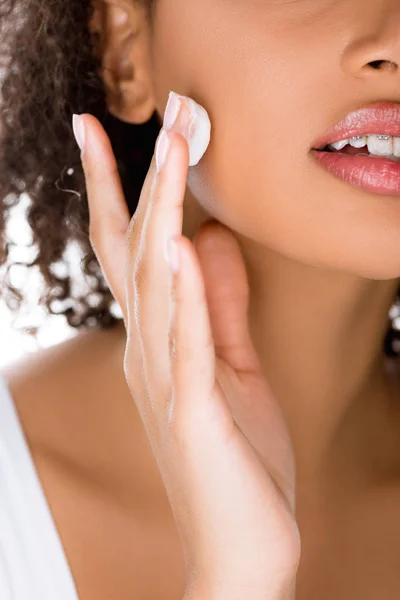 Vue recadrée de fille afro-américaine avec appareil dentaire appliquant crème visage, isolé sur blanc — Photo de stock