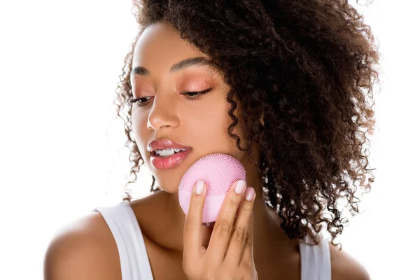 Hermosa chica afroamericana usando cepillo facial limpiador de silicona, aislado en blanco - foto de stock